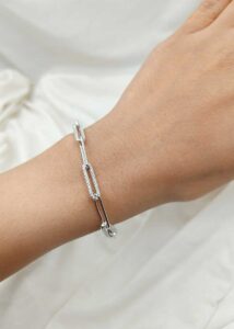 Layered sterling silver bracelets stacked on woman’s